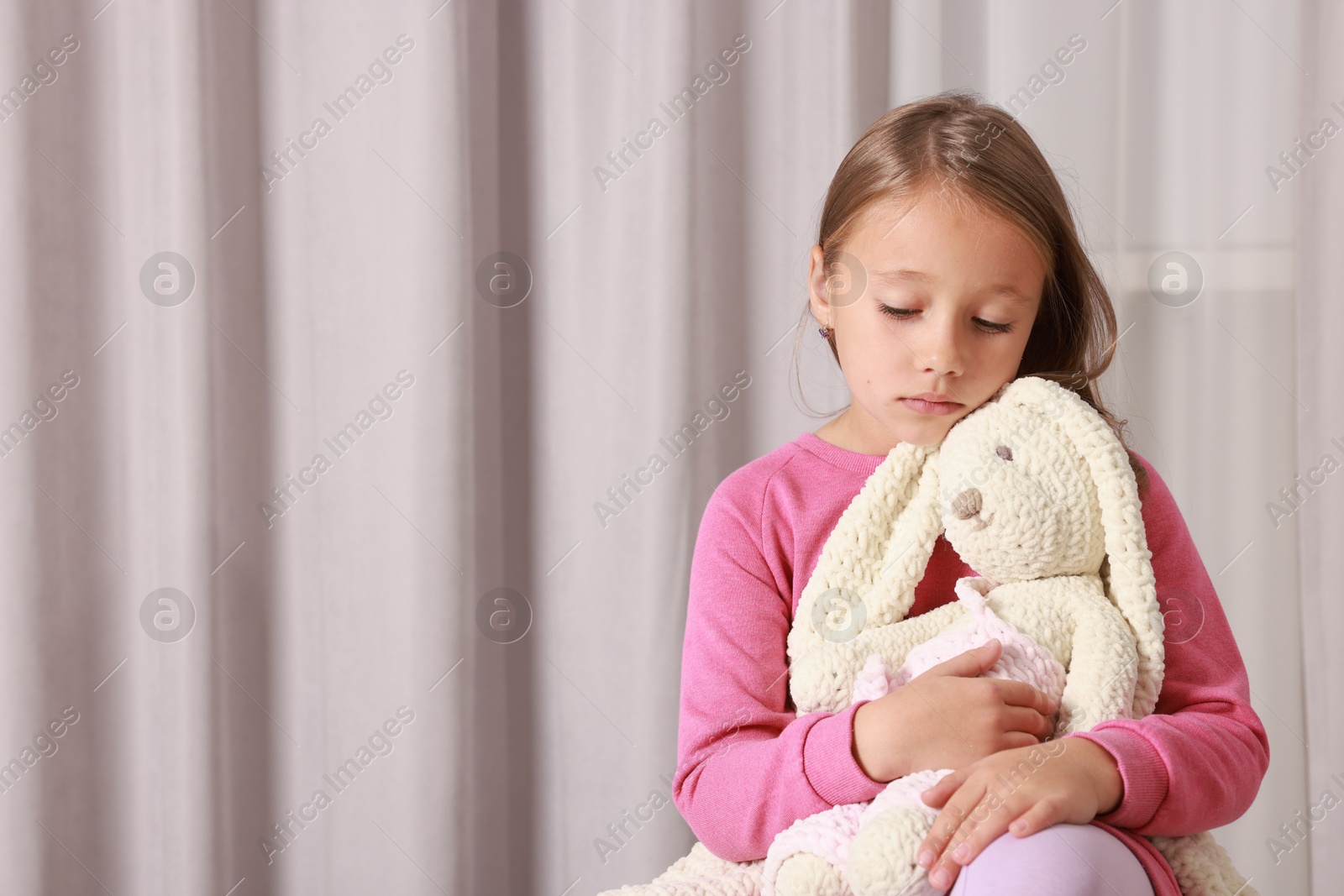 Photo of Autism concept. Lonely little girl with toy bunny at home, space for text