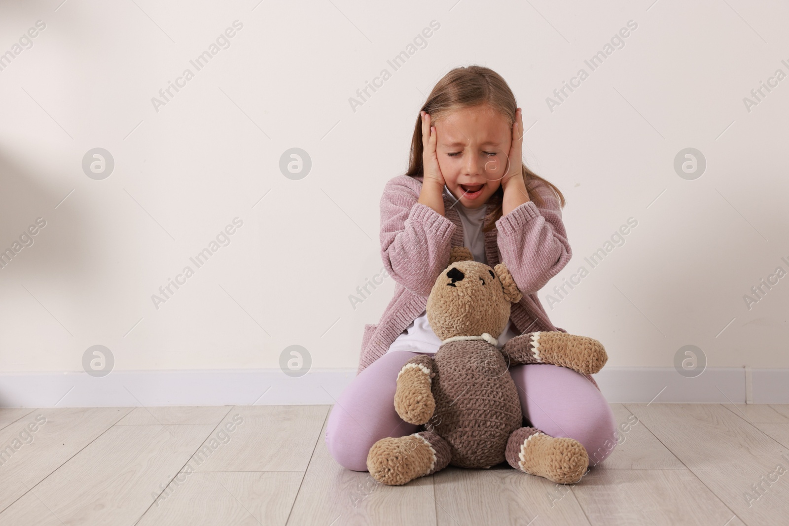 Photo of Autism concept. Scared little girl covering her ears at home, space for text