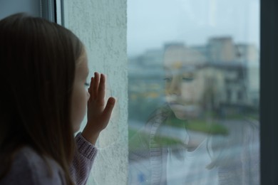 Autism concept. Lonely little girl near window at home, space for text