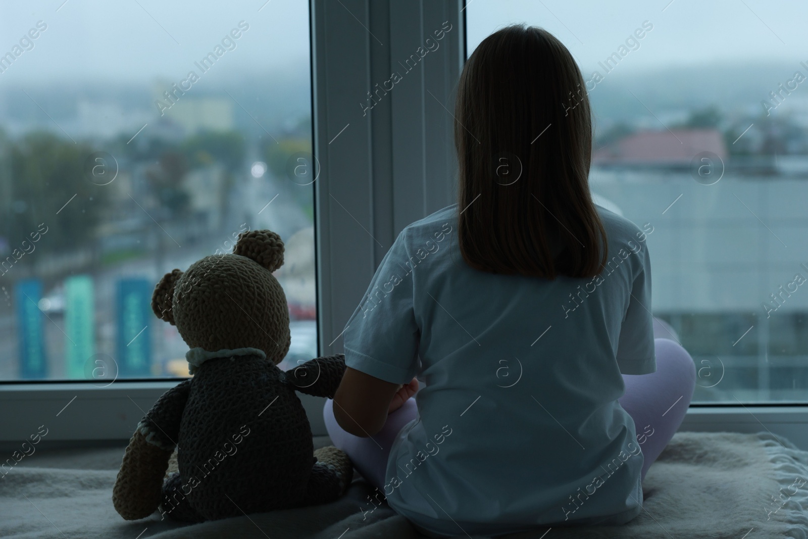 Photo of Autism concept. Lonely little girl near window at home