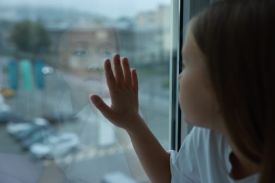 Autism concept. Lonely little girl near window at home