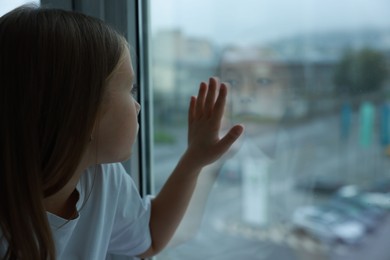 Autism concept. Lonely little girl near window at home, space for text