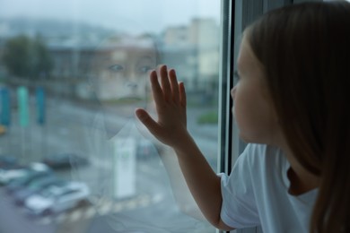 Autism concept. Lonely little girl near window at home, space for text