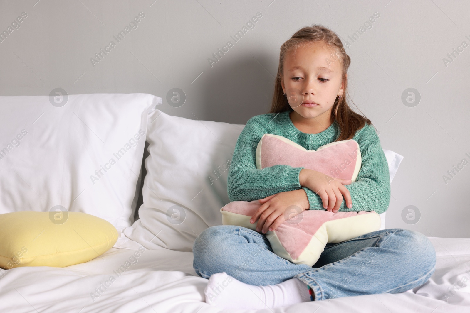 Photo of Autism concept. Lonely little girl with pillow on bed at home