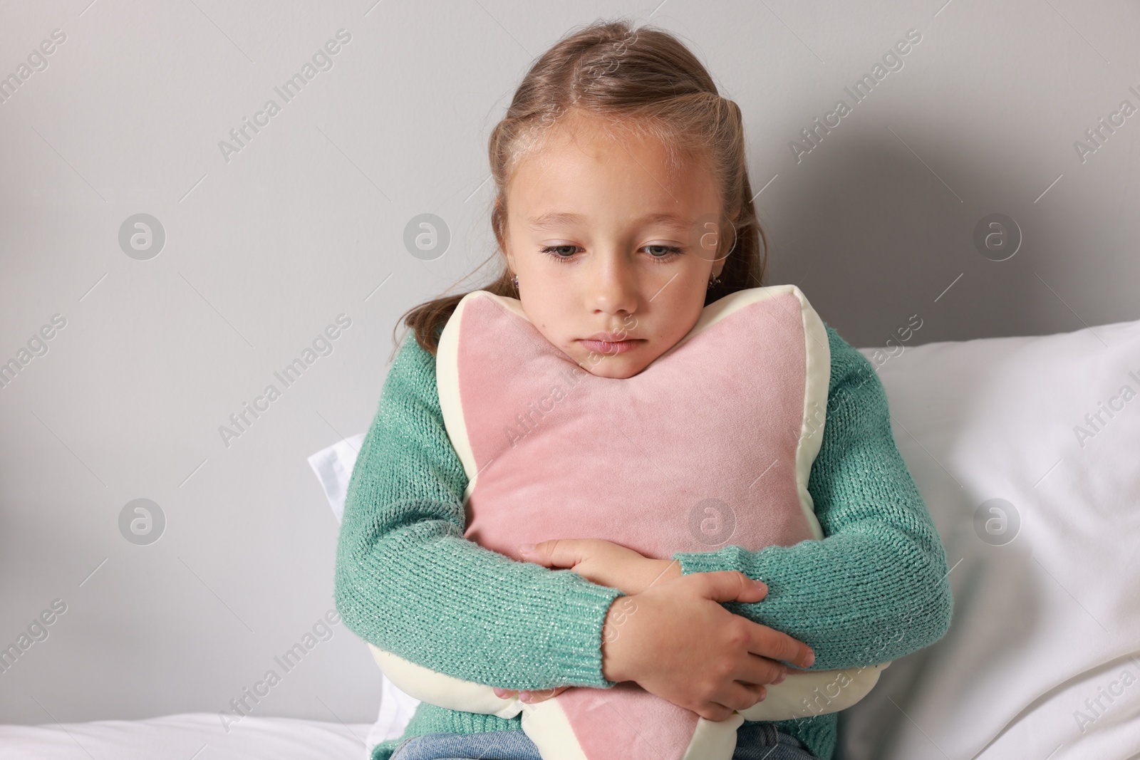 Photo of Autism concept. Lonely little girl with pillow on bed at home