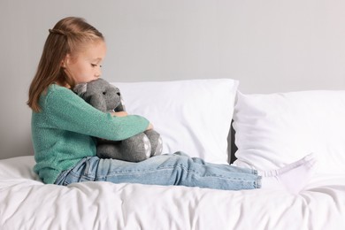 Photo of Autism concept. Lonely little girl with toy bunny on bed at home