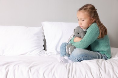 Autism concept. Lonely little girl with toy bunny on bed at home