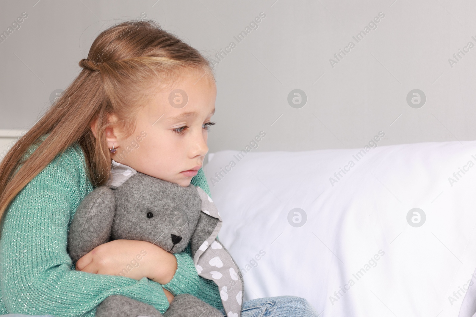 Photo of Autism concept. Lonely little girl with toy bunny on bed at home, space for text