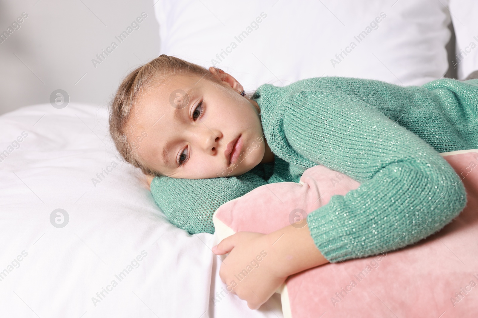 Photo of Autism concept. Lonely little girl with pillow lying on bed at home