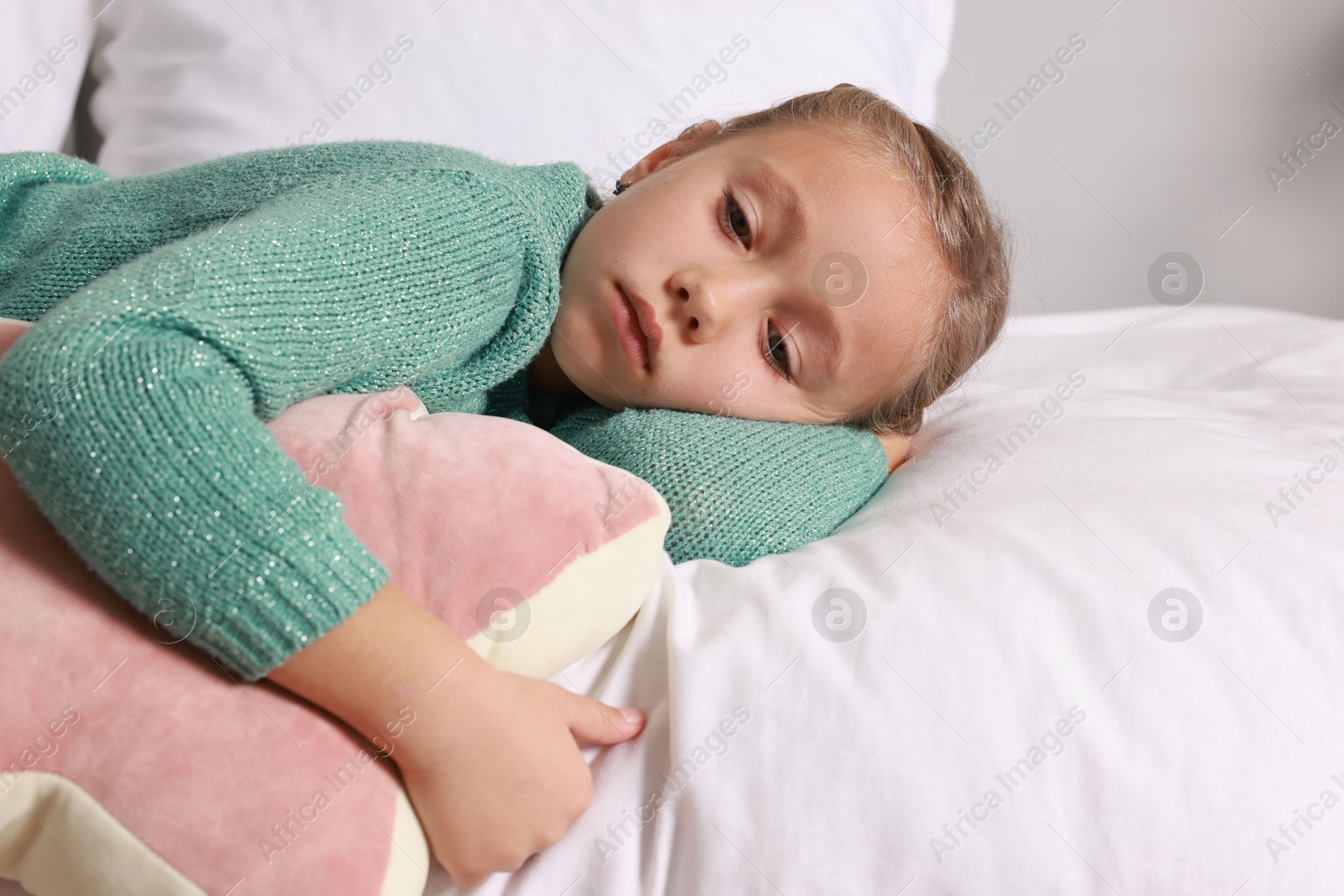 Photo of Autism concept. Lonely little girl with pillow lying on bed at home