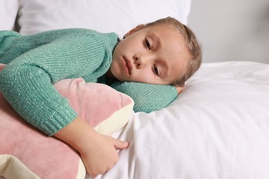 Autism concept. Lonely little girl with pillow lying on bed at home