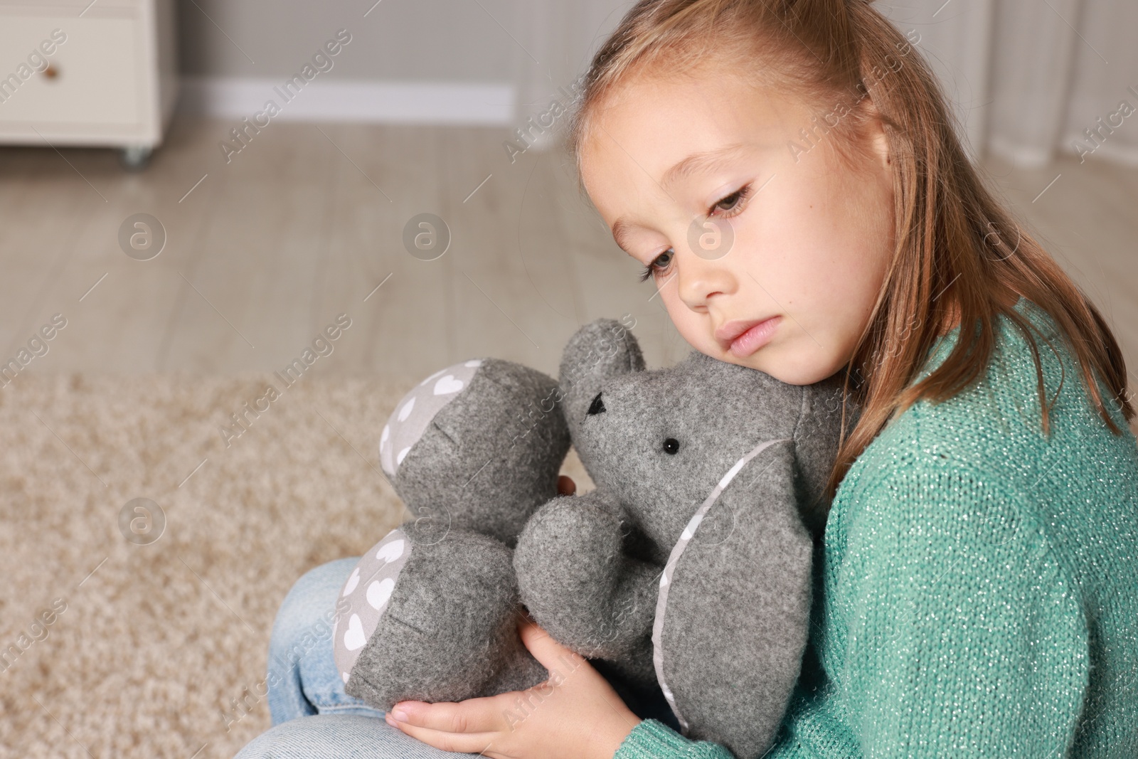 Photo of Autism concept. Lonely little girl with toy bunny at home