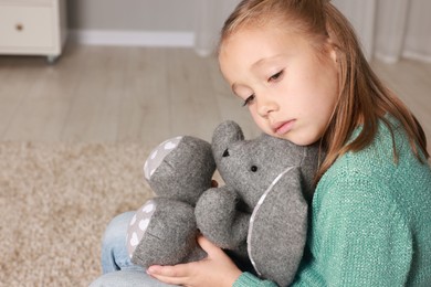 Autism concept. Lonely little girl with toy bunny at home