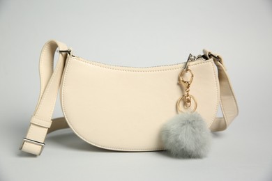 Photo of Leather bag with faux fur keychain on grey background