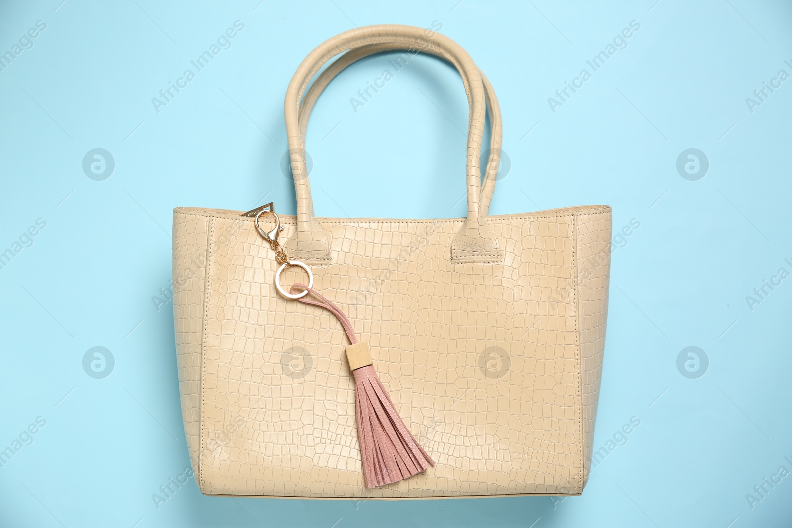 Photo of Bag with pink leather keychain on light blue background, top view