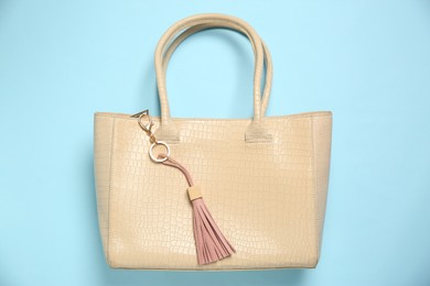 Photo of Bag with pink leather keychain on light blue background, top view