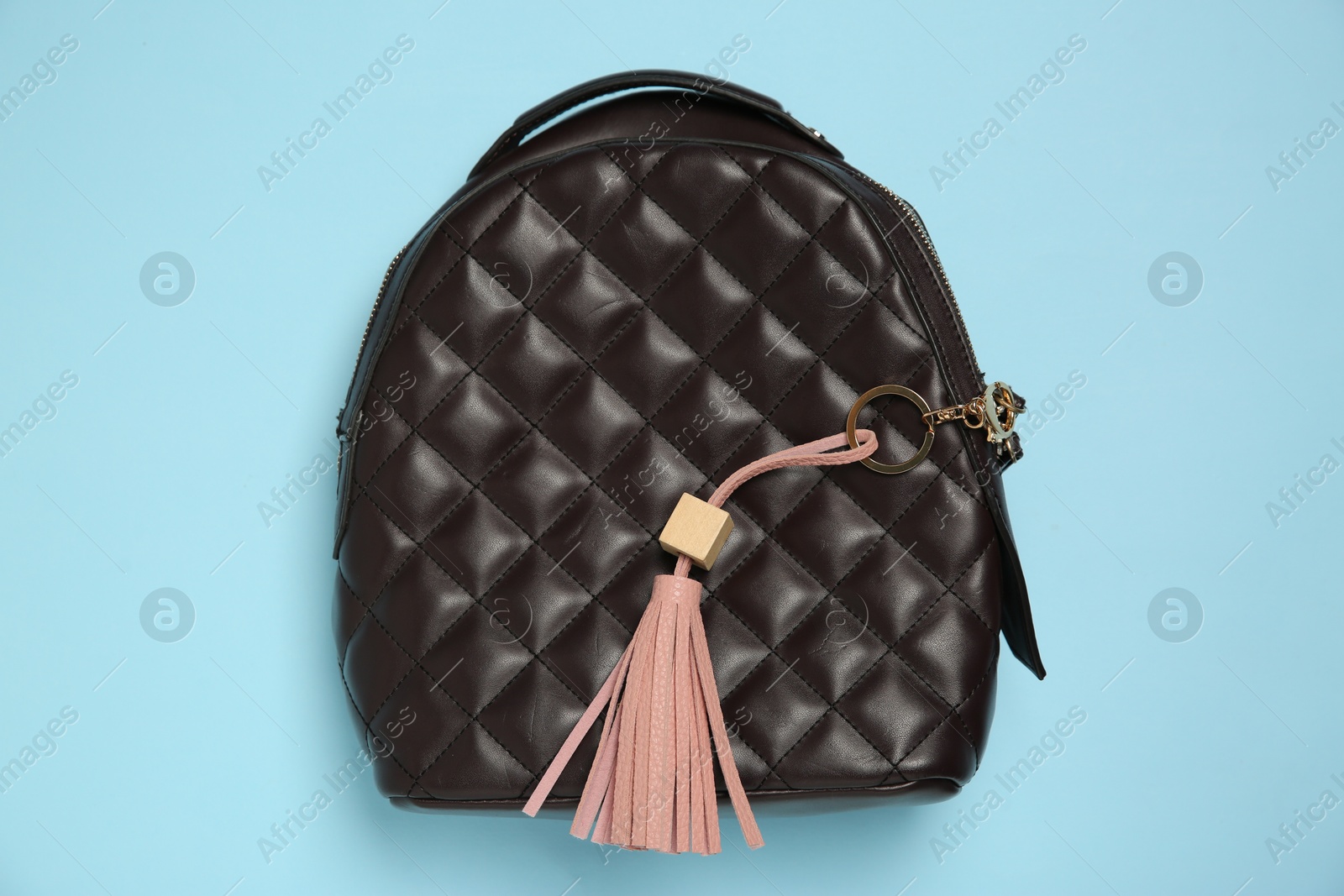 Photo of Backpack with pink leather keychain on light blue background, top view