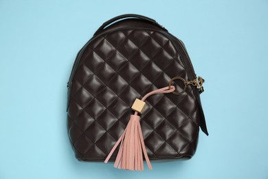 Photo of Backpack with pink leather keychain on light blue background, top view