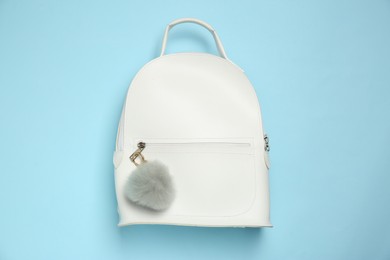 Photo of Backpack with grey faux fur keychain on light blue background, top view