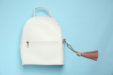 Photo of Backpack with pink leather keychain on light blue background, top view