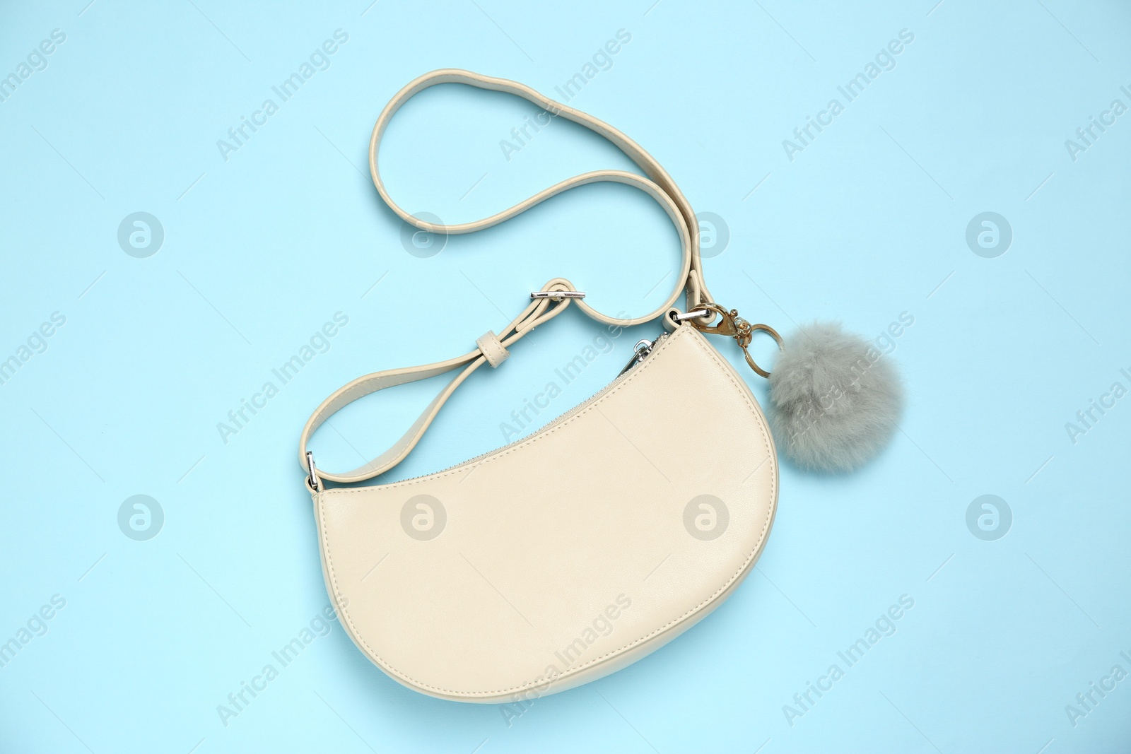 Photo of Bag with grey faux fur keychain on light blue background, top view