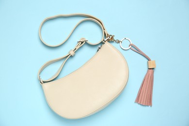 Photo of Bag with pink leather keychain on light blue background, top view