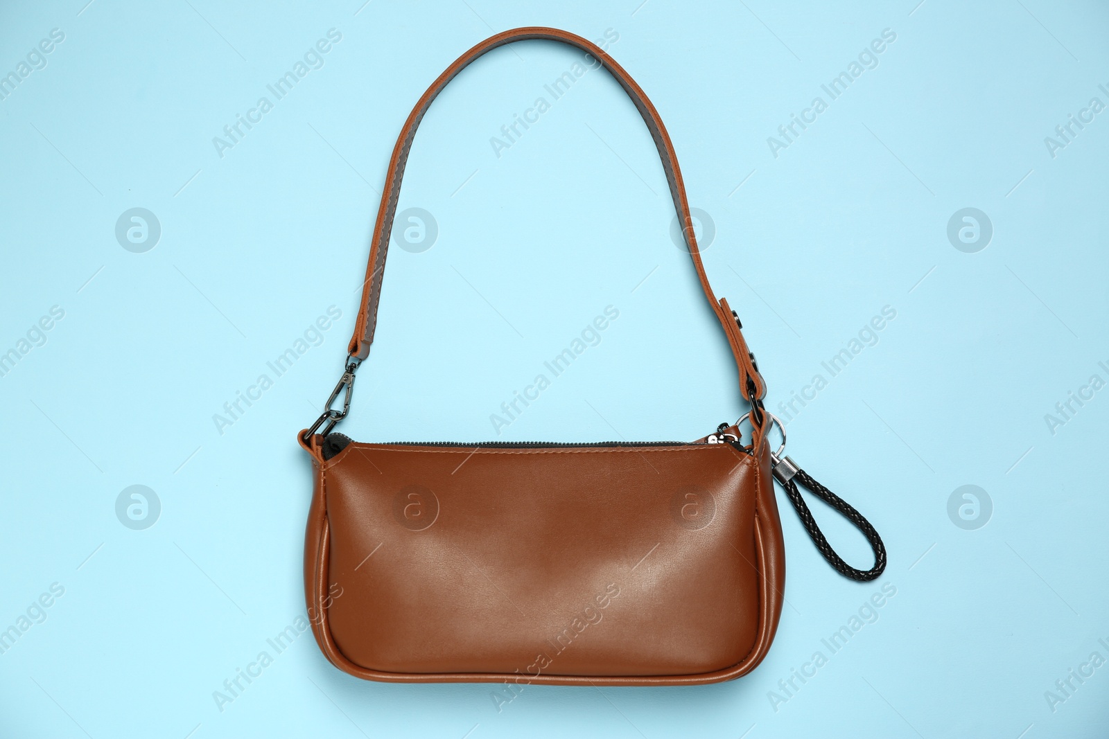 Photo of Bag with black leather keychain on light blue background, top view