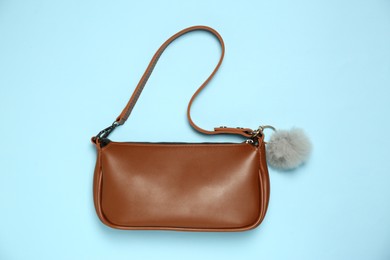 Photo of Bag with grey faux fur keychain on light blue background, top view