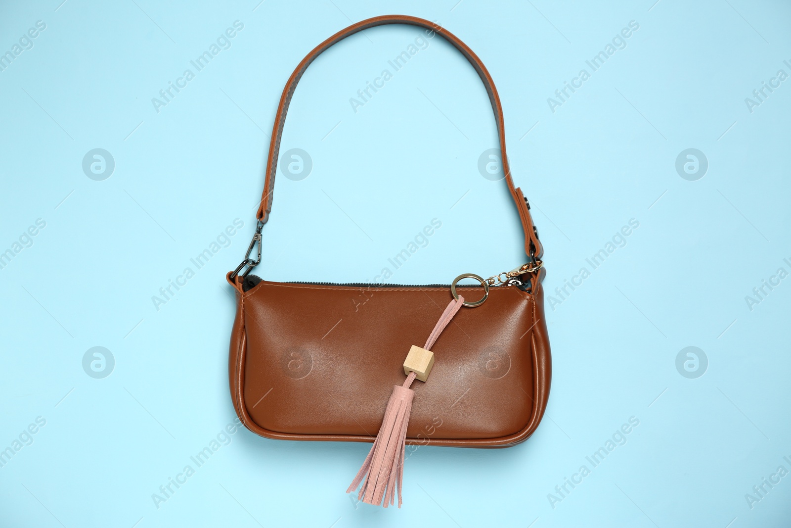 Photo of Bag with pink leather keychain on light blue background, top view