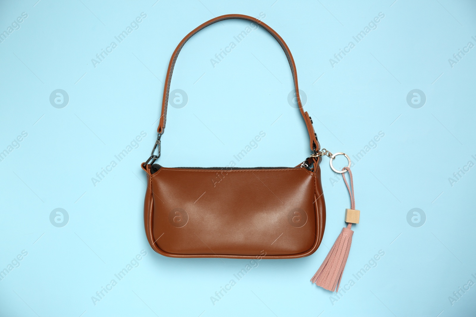 Photo of Bag with pink leather keychain on light blue background, top view