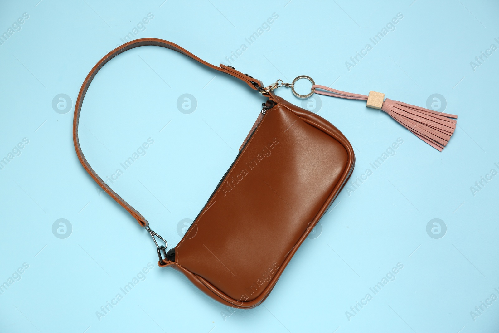 Photo of Bag with pink leather keychain on light blue background, top view