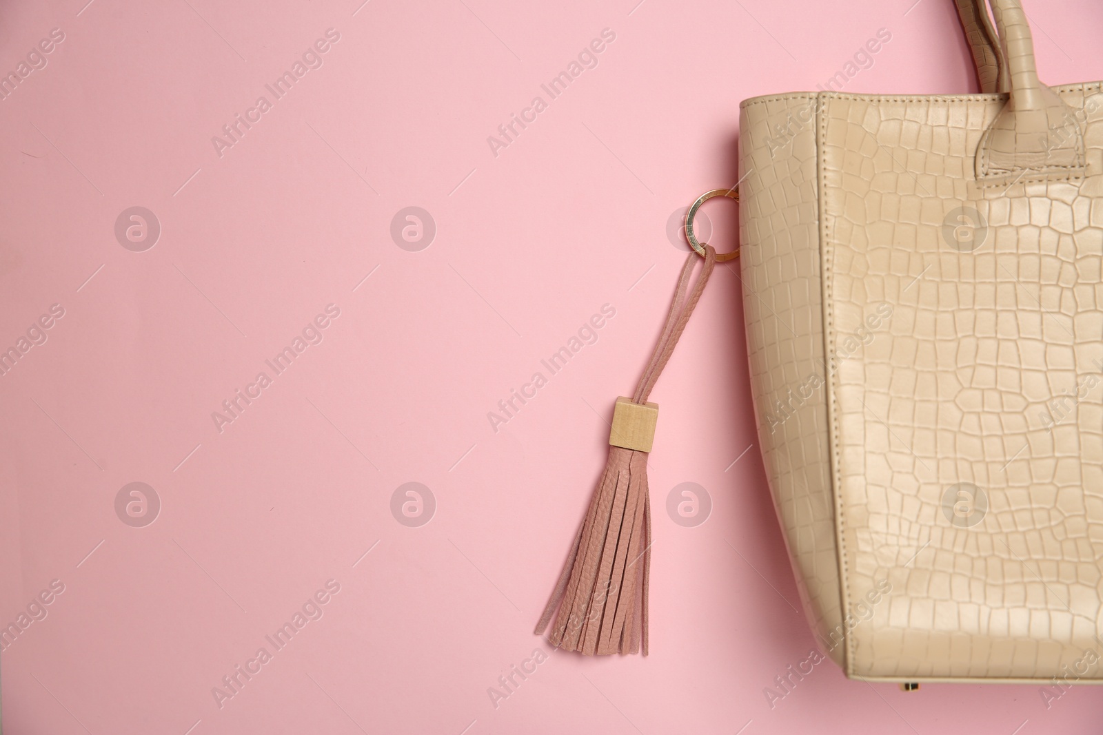 Photo of Bag with leather keychain on pink background, top view. Space for text