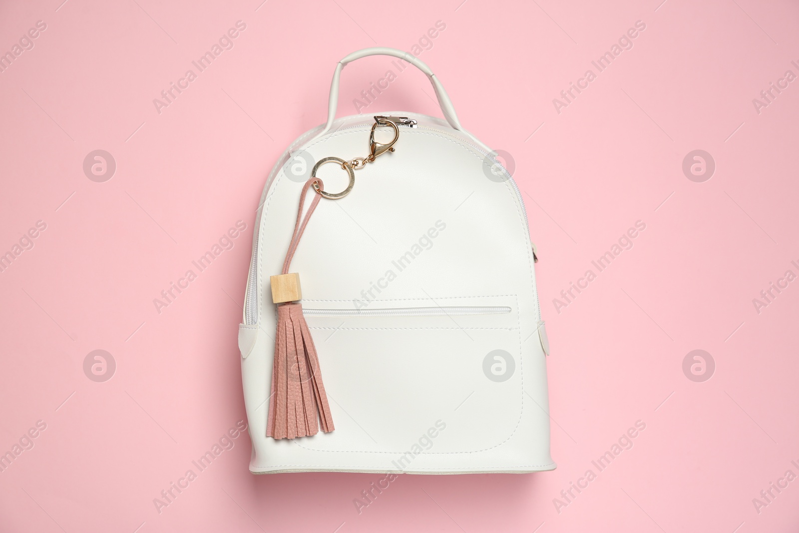 Photo of Backpack with leather keychain on pink background, top view