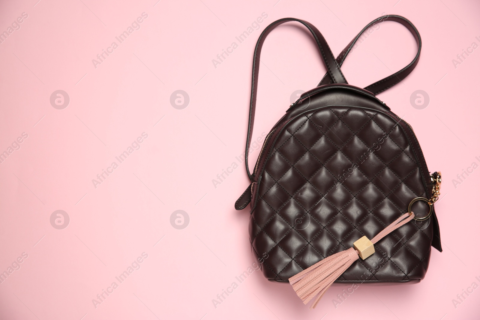 Photo of Backpack with leather keychain on pink background, top view. Space for text