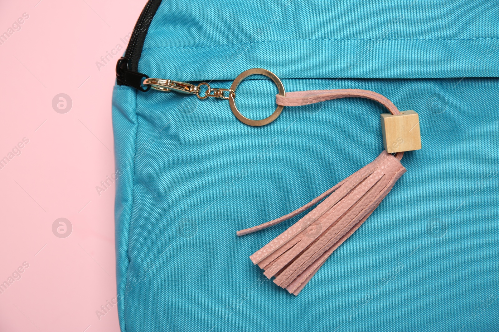 Photo of Backpack with leather keychain on pink background, top view