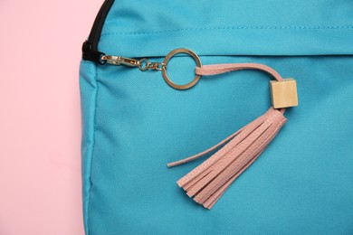 Backpack with leather keychain on pink background, top view