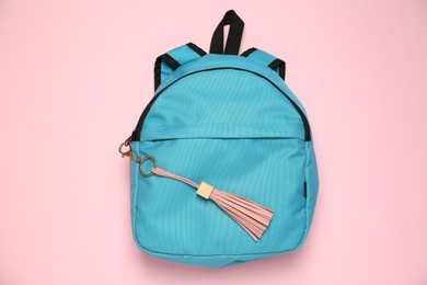 Photo of Backpack with leather keychain on pink background, top view