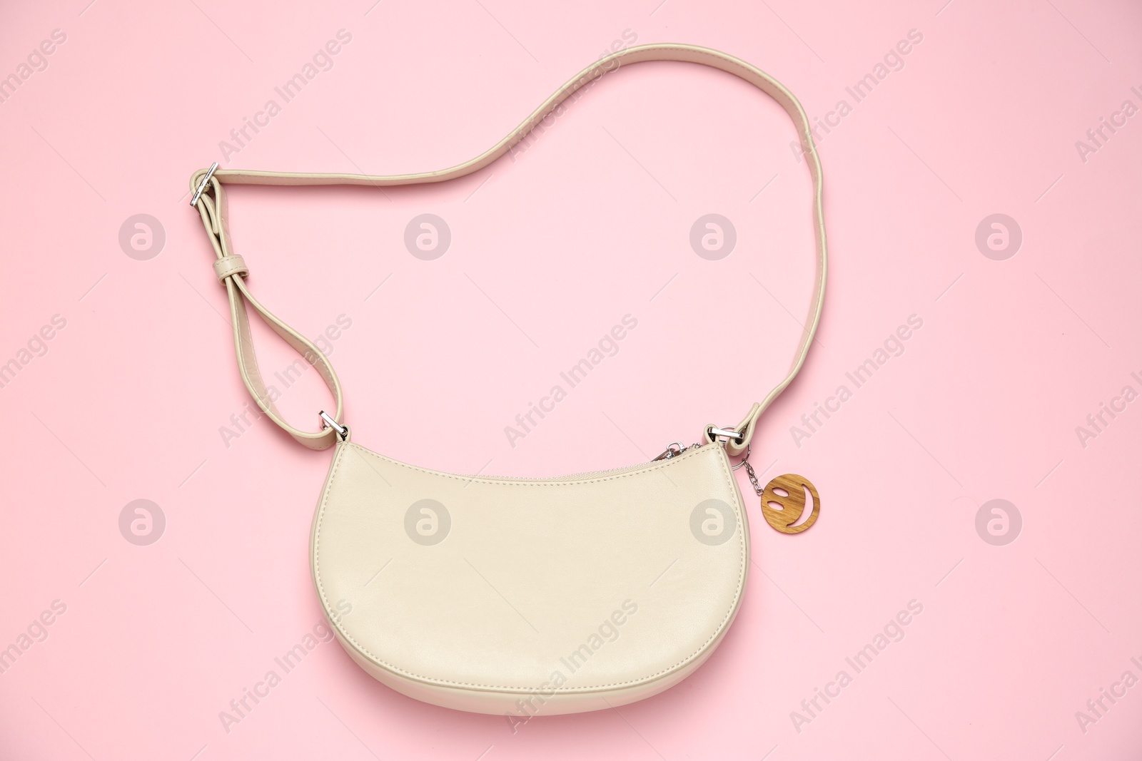 Photo of Bag with wooden keychain in shape of smiley face on pink background, top view