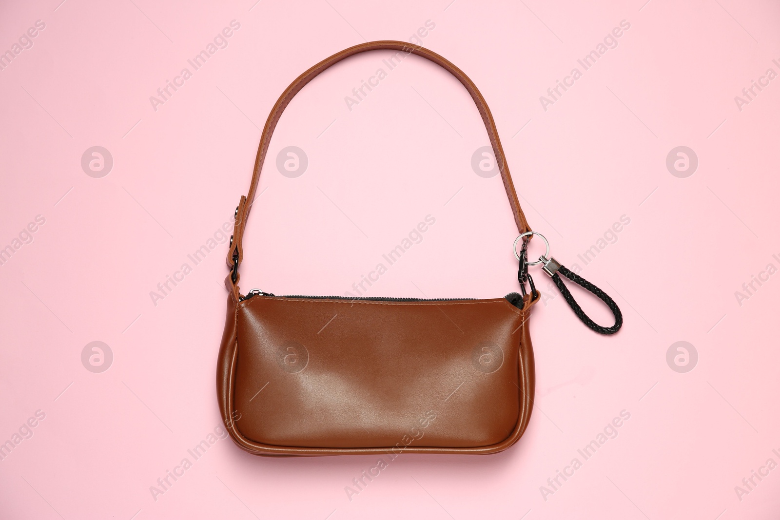 Photo of Brown bag with black leather keychain on pink background, top view