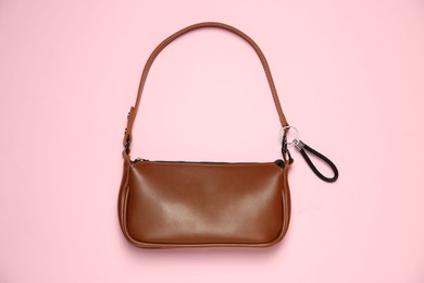 Photo of Brown bag with black leather keychain on pink background, top view