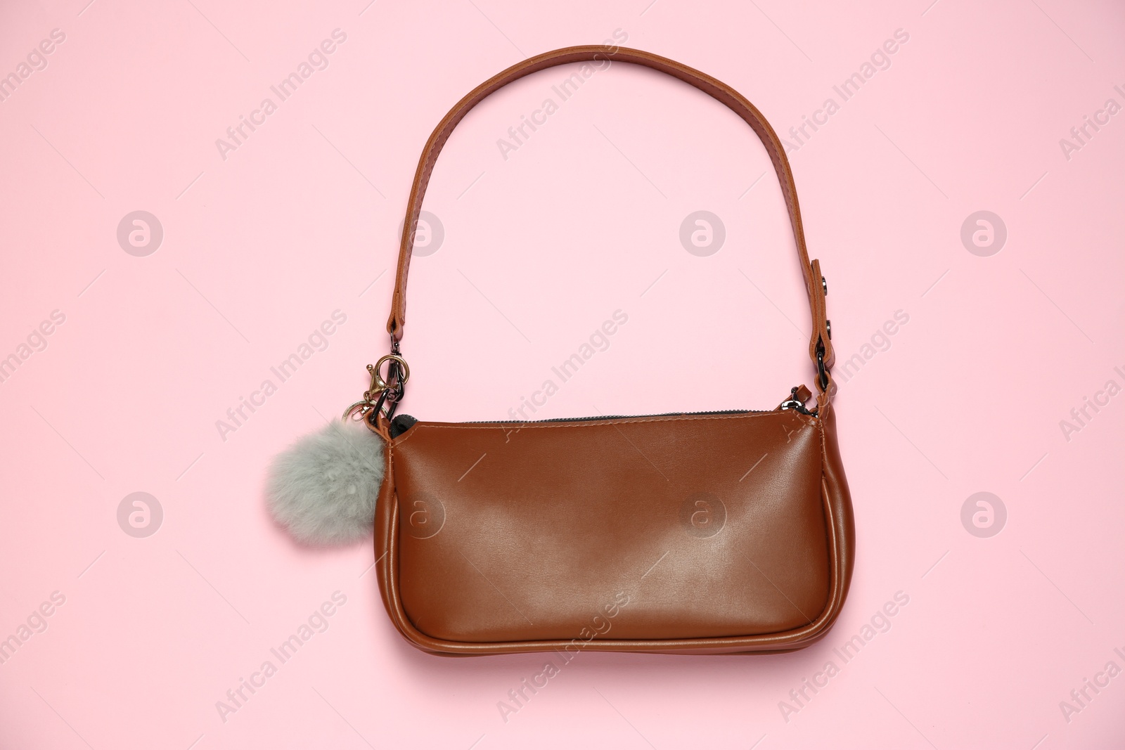 Photo of Brown bag with grey faux fur keychain on pink background, top view