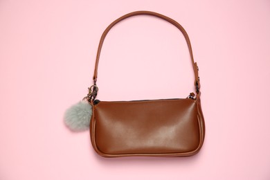 Photo of Brown bag with grey faux fur keychain on pink background, top view