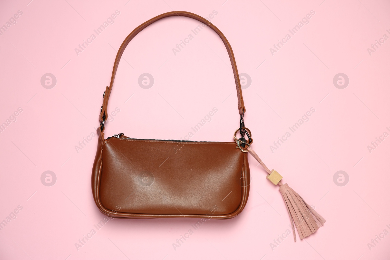 Photo of Brown bag with leather keychain on pink background, top view