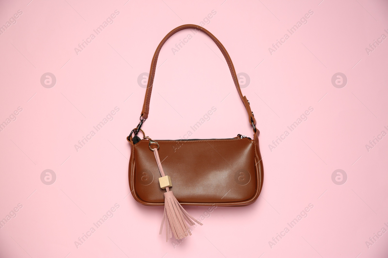 Photo of Brown bag with leather keychain on pink background, top view