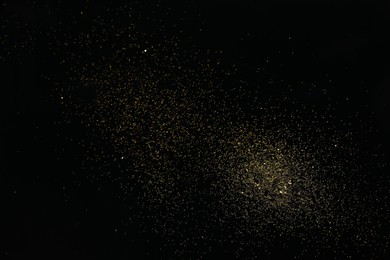 Photo of Beautiful shiny golden glitter on black background, top view