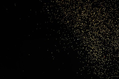 Photo of Beautiful shiny golden glitter on black background, top view