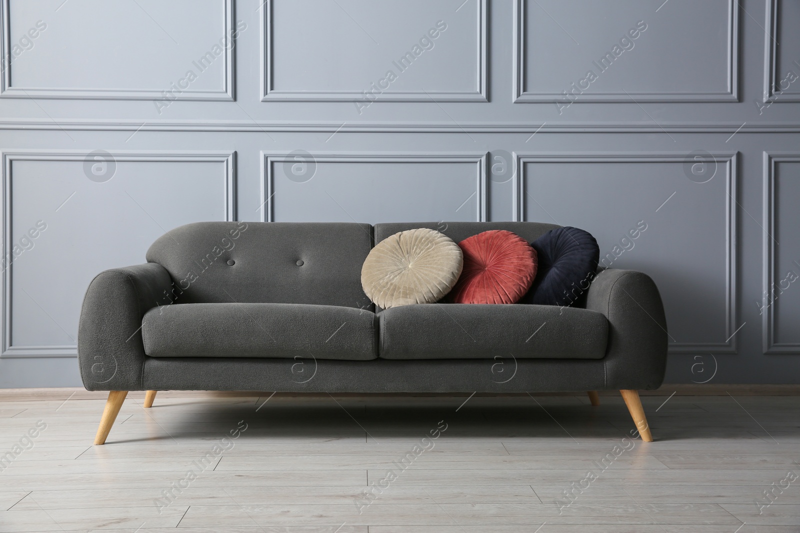 Photo of Stylish sofa with cushions near grey wall