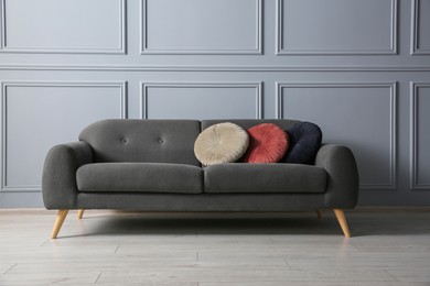 Stylish sofa with cushions near grey wall