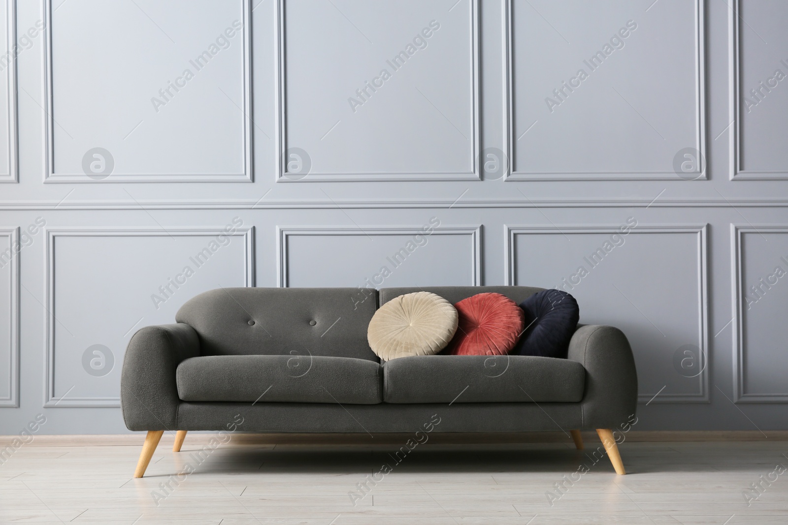 Photo of Stylish sofa with cushions near grey wall