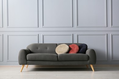 Stylish sofa with cushions near grey wall